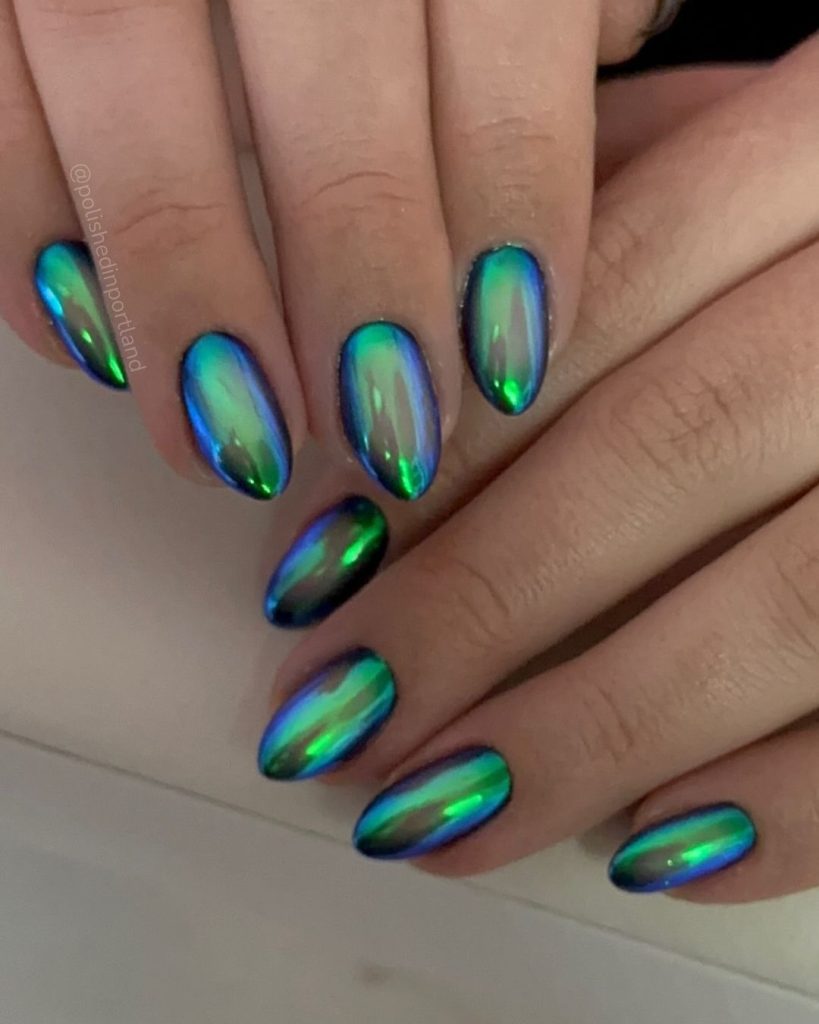 A pair of hands showing off green, almond-shaped aura nails