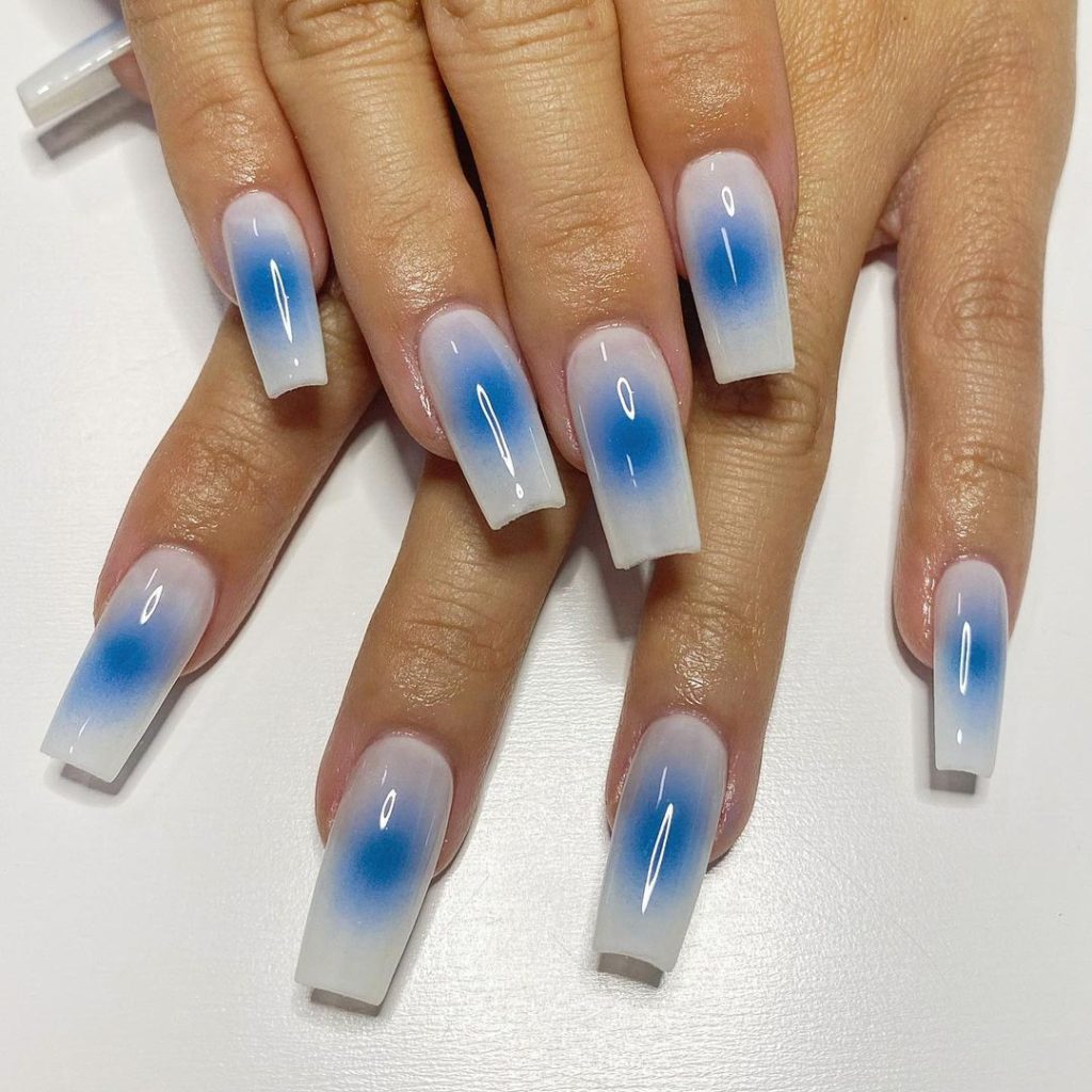 A pair of hands showing off blue, coffin-shaped aura nails