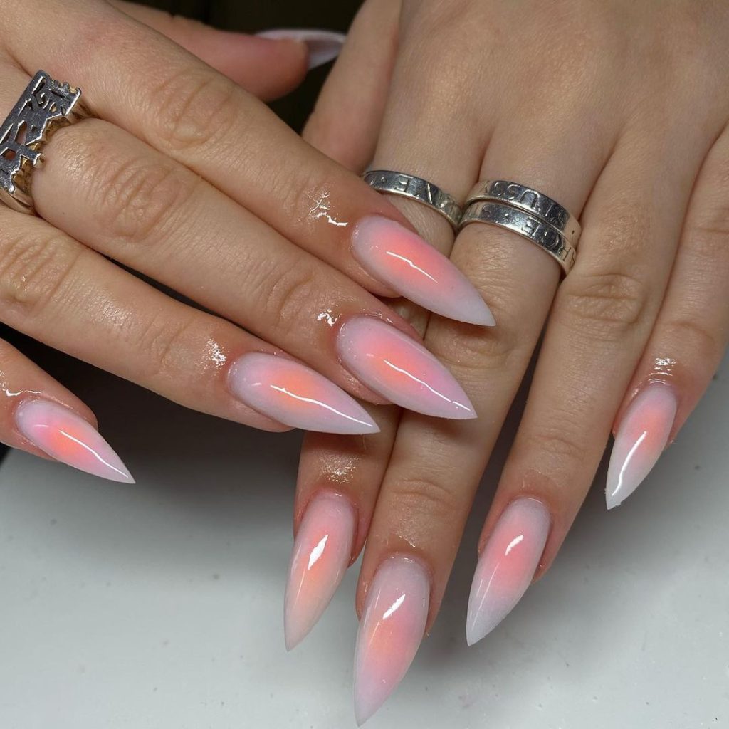 A pair of hands showing off orange, almond-shaped aura nails