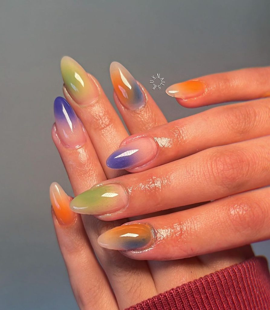 A pair of hands showing off multi-color, almond-shaped aura nails