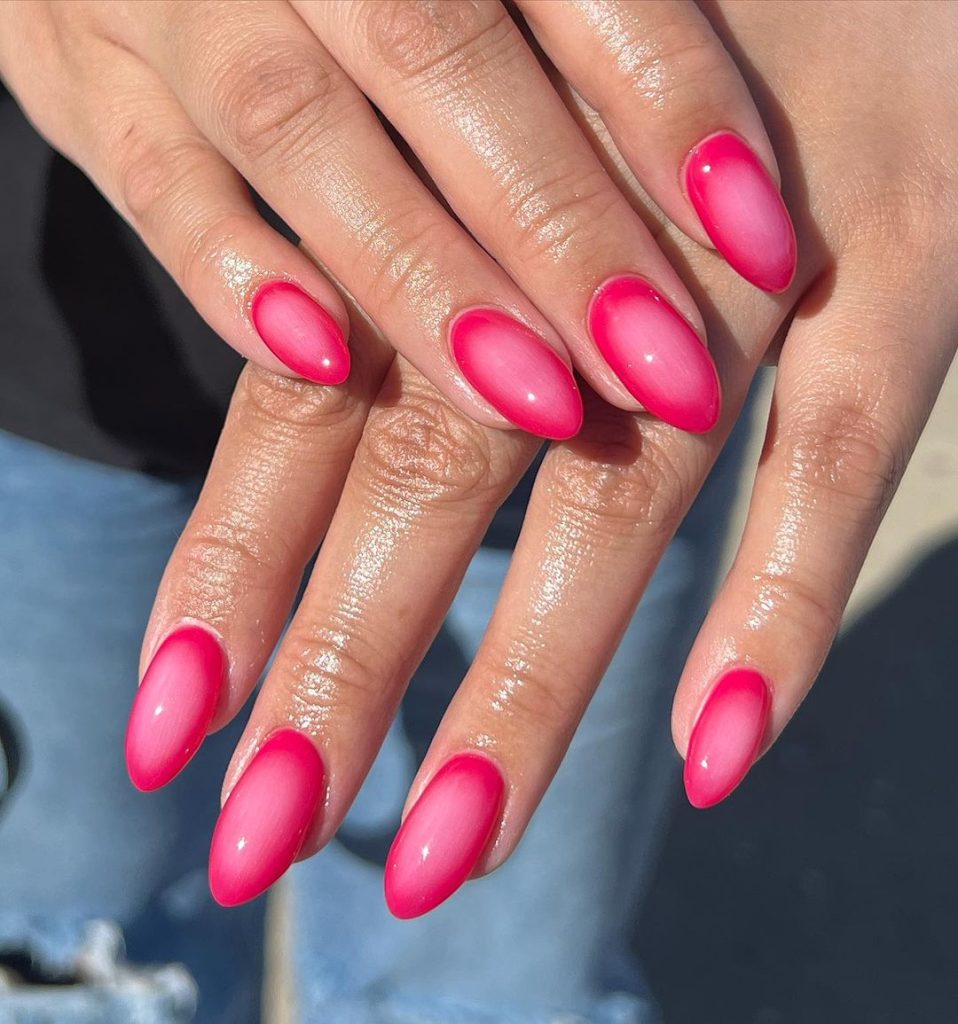 A pair of hands showing off red, almond-shaped aura nails
