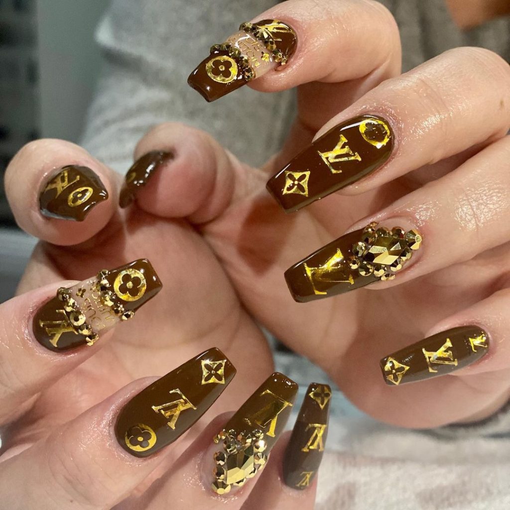 dark brown and gold nails with LV designs